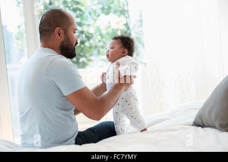 Père jouant avec son bébé sur le lit Banque D'Images