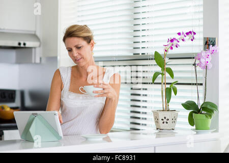 Caucasian woman using digital tablet in kitchen Banque D'Images