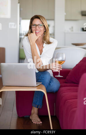 Caucasian woman using laptop on sofa Banque D'Images