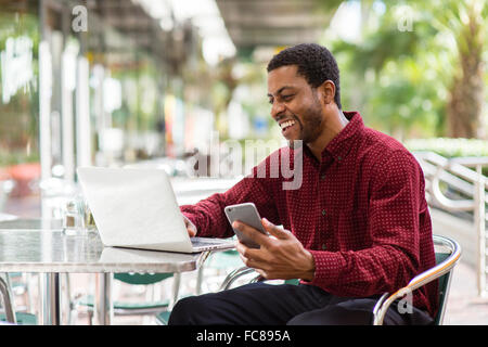 Black businessman using cell phone in cafe Banque D'Images