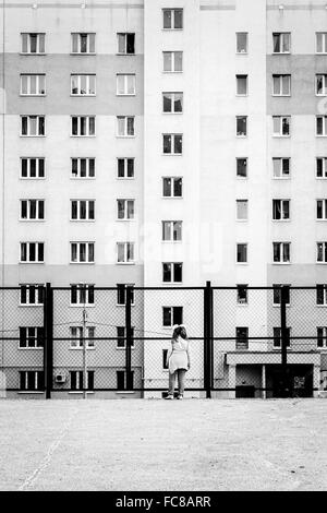 UFA - RUSSIE 22ÈME MAI 2014 - Jeune enfant regarde son lointain à travers un grillage à un grand appartement dans un bloc russe typique Banque D'Images