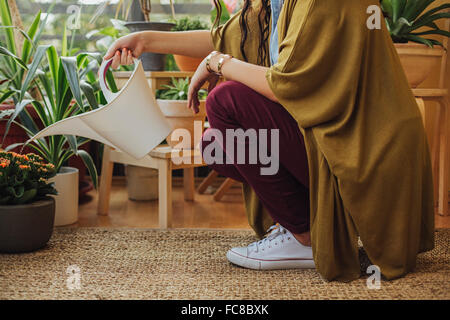 Caucasian woman watering potted plants Banque D'Images