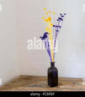 Fleurs séchées dans un vase bouteille bleu sur bois Banque D'Images