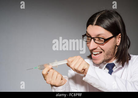 Male doctor holding syringe contre gray Banque D'Images