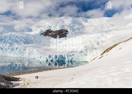 Deux randonneurs entouré de montagnes couvertes de glace et les glaciers en Neko Harbour, l'Antarctique, régions polaires Banque D'Images