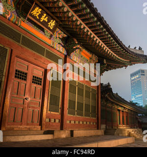 Palais Deoksugung, bâtiment traditionnel coréen, éclairé au crépuscule, avec un bâtiment moderne dans la distance, Séoul, Corée du Sud, Asie Banque D'Images