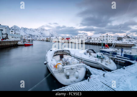 Le typique village de pêcheurs de Henningsvær entouré de montagnes enneigées et la mer froide, îles Lofoten, Norvège Banque D'Images