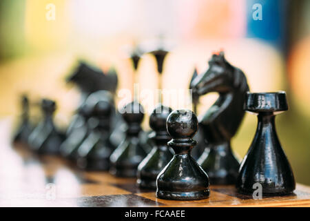 Vieux Noir debout sur les chiffres d'Échecs échiquier en bois Banque D'Images