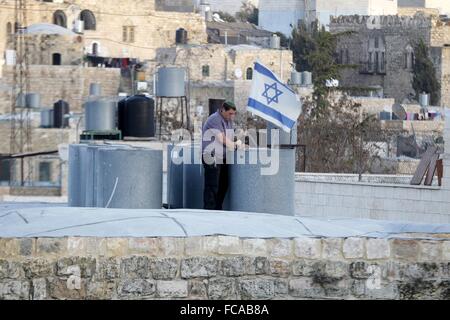 Hébron, en Cisjordanie, en territoire palestinien. 21 Jan, 2016. Un colon israélien met un drapeau israélien sur le toit d'une maison palestinienne dans un immeuble dans le centre de la ville palestinienne d'Hébron, provoquant de violents affrontements au milieu d'une réclamation contestée de la propriété, selon des témoins, le 21 janvier 2016. Le bâtiment est à proximité de la place aux juifs religieux connu comme le Tombeau des Patriarches et des Musulmans sous la mosquée au coeur de la ville de point sud de la Cisjordanie. Credit : ZUMA Press, Inc./Alamy Live News Banque D'Images