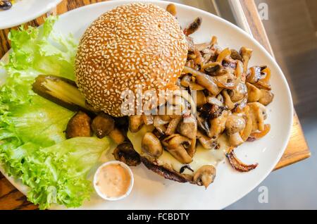 Un plat avec un hamburger avec des champignons sautés sur le dessus, le sésame pain bun, letuce et mayonnaise. Un délicieux hamburger grillé, une aug Banque D'Images