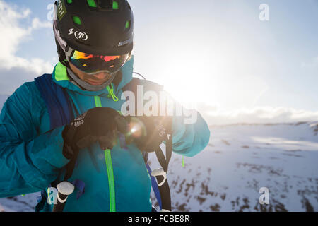 Un homme boucles son sac à dos alors qu'il se prépare à skier sur une journée très ventée en Islande. Banque D'Images