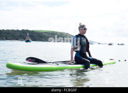 Femme assise sur un paddle board dans la mer à de graves Banque D'Images