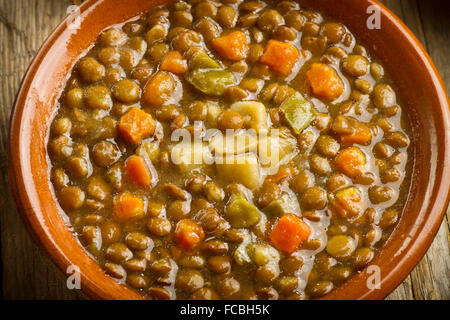 Gros plan d'une soupe aux lentilles de légumes sur une table en bois, avec les lentilles, les carottes, le poivron et la pomme de terre Banque D'Images