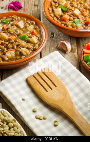 Soupe de lentilles aux légumes sur deux pots en argile et adjuvants sur table en bois Banque D'Images