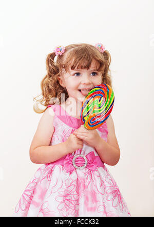 Portrait of cute little Girl with big lollipop colorés sur un fond clair Banque D'Images