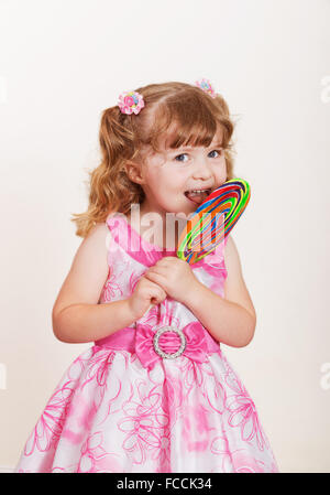 Portrait of cute little Girl with big lollipop colorés sur un fond clair Banque D'Images