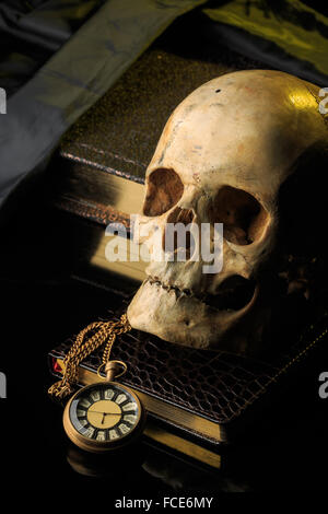 Crâne humain sur un livre près de l'horloge. concept de magie noire Banque D'Images