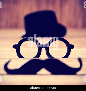 Une moustache, une paire de lunettes et un chapeau noir placé dans différents niveaux formant le visage d'un homme Banque D'Images