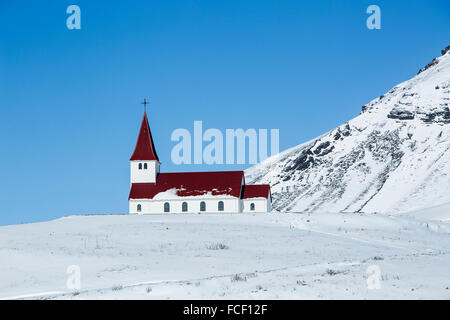 Eglise de Vik en hiver avec les montagnes enneigées en Islande Banque D'Images