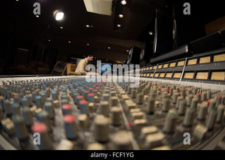 Vue latérale d'une personne travaillant sur une série e ssl du mixage sonore 24 et Apple Mac avec haut-parleurs studio dans un studio d'enregistrement Banque D'Images