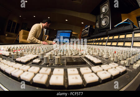 Vue latérale d'une personne travaillant sur une série e ssl du mixage sonore 24 et Apple Mac avec haut-parleurs studio dans un studio d'enregistrement Banque D'Images