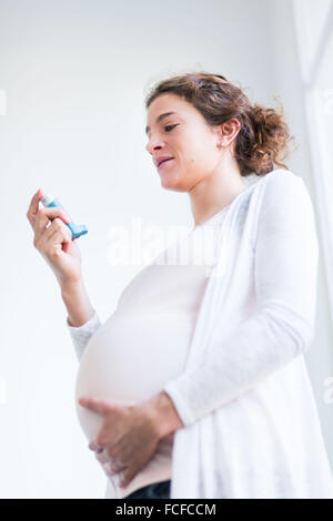 Femme enceinte à l'aide d'un inhalateur d'asthme. Banque D'Images