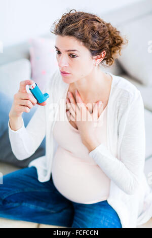 Femme enceinte à l'aide d'un inhalateur d'asthme. Banque D'Images