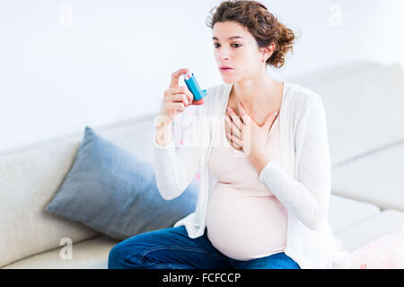 Femme enceinte à l'aide d'un inhalateur d'asthme. Banque D'Images