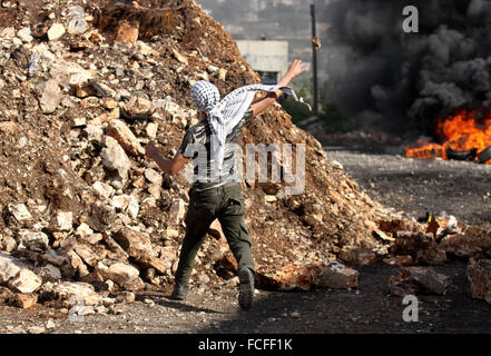 Naplouse, Cisjordanie, territoire palestinien. 22 janvier, 2016. Un manifestant palestinien lance des pierres en direction des forces de sécurité israéliennes au cours d'affrontements à la suite d'une protestation contre l'expropriation de terres palestiniennes par Israël dans le village de Kafr Qaddum, près de la ville du nord de Naplouse, le 22 janvier 2016 Credit : Nedal Eshtayah/APA/Images/fil ZUMA Alamy Live News Banque D'Images