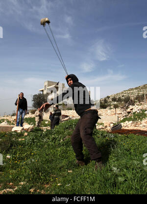 Naplouse, Cisjordanie, territoire palestinien. 22 janvier, 2016. Un manifestant palestinien lance des pierres en direction des forces de sécurité israéliennes au cours d'affrontements à la suite d'une protestation contre l'expropriation de terres palestiniennes par Israël dans le village de Kafr Qaddum, près de la ville du nord de Naplouse, le 22 janvier 2016 Credit : Nedal Eshtayah/APA/Images/fil ZUMA Alamy Live News Banque D'Images