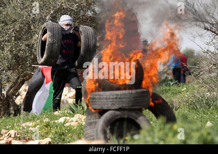 Naplouse, Cisjordanie, territoire palestinien. 22 janvier, 2016. Un manifestant palestinien porte pneumatiques lors d'affrontements avec les forces de sécurité israéliennes après une protestation contre l'expropriation de terres palestiniennes par Israël dans le village de Kafr Qaddum, près de la ville du nord de Naplouse, le 22 janvier 2016 Credit : Nedal Eshtayah/APA/Images/fil ZUMA Alamy Live News Banque D'Images