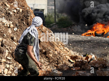 Naplouse, Cisjordanie, territoire palestinien. 22 janvier, 2016. Un manifestant palestinien lance des pierres en direction des forces de sécurité israéliennes au cours d'affrontements à la suite d'une protestation contre l'expropriation de terres palestiniennes par Israël dans le village de Kafr Qaddum, près de la ville du nord de Naplouse, le 22 janvier 2016 Credit : Nedal Eshtayah/APA/Images/fil ZUMA Alamy Live News Banque D'Images