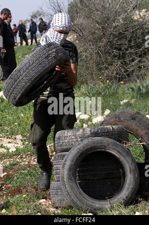 Naplouse, Cisjordanie, territoire palestinien. 22 janvier, 2016. Un manifestant palestinien porte pneumatiques lors d'affrontements avec les forces de sécurité israéliennes après une protestation contre l'expropriation de terres palestiniennes par Israël dans le village de Kafr Qaddum, près de la ville du nord de Naplouse, le 22 janvier 2016 Credit : Nedal Eshtayah/APA/Images/fil ZUMA Alamy Live News Banque D'Images