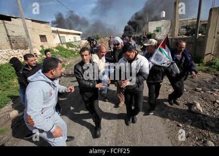 Naplouse, Cisjordanie, territoire palestinien. 22 janvier, 2016. Les Palestiniens portent un manifestant blessé lors d'affrontements avec les forces de sécurité israéliennes après une protestation contre l'expropriation de terres palestiniennes par Israël dans le village de Kafr Qaddum, près de la ville du nord de Naplouse, le 22 janvier 2016 Credit : Nedal Eshtayah/APA/Images/fil ZUMA Alamy Live News Banque D'Images