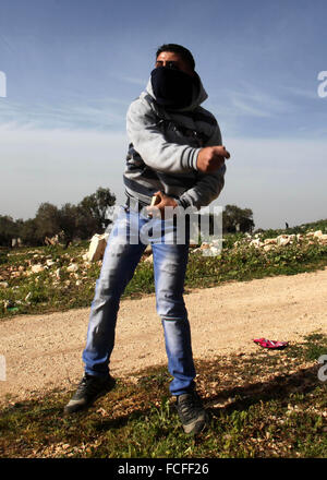 Naplouse, Cisjordanie, territoire palestinien. 22 janvier, 2016. Un manifestant palestinien lance des pierres en direction des forces de sécurité israéliennes au cours d'affrontements à la suite d'une protestation contre l'expropriation de terres palestiniennes par Israël dans le village de Kafr Qaddum, près de la ville du nord de Naplouse, le 22 janvier 2016 Credit : Nedal Eshtayah/APA/Images/fil ZUMA Alamy Live News Banque D'Images