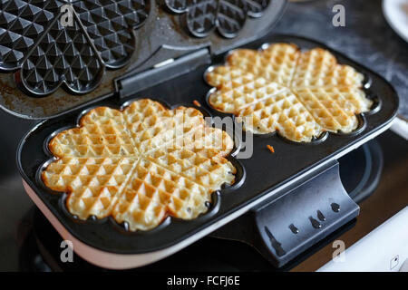 Deux gaufres maison sur gaufrier électrique fer à repasser au-dessus de cuisinière dans la cuisine Banque D'Images