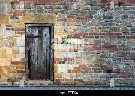 En bois de chêne ancien porte cloutée et cotswold stone et mur de brique rouge. Arles, France Banque D'Images