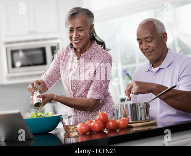 Un couple d'âge mûr, un homme et une femme dans sa cuisine à préparer un repas. Banque D'Images