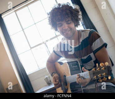 Loft vivant. Un jeune homme qui joue de la guitare. Banque D'Images