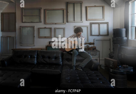 Décoration Loft. Un mur décoré de photos dans des cadres, à l'envers pour montrer le dos. Un homme jouant de la guitare. Banque D'Images