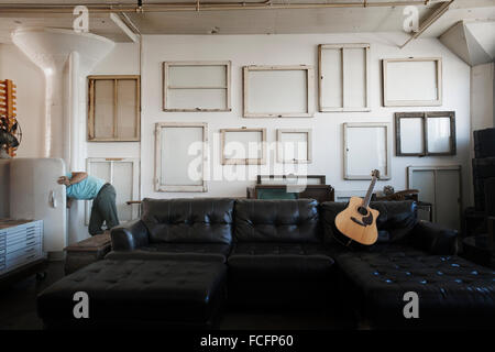 Décoration Loft. Un mur décoré de photos dans des cadres, à l'envers pour montrer le dos. Un homme à l'occasion d'une porte de réfrigérateur en se penchant. Banque D'Images