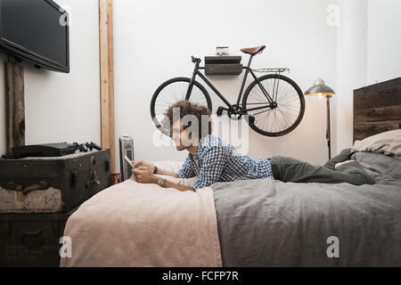 Loft vivant. Un vélo accroché à un mur. Un homme à l'aide d'une tablette numérique. Banque D'Images