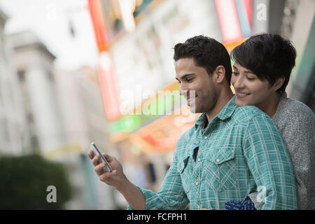 Un couple, man and woman hugging sur une rue de la ville. Homme tenant un téléphone intelligent. Banque D'Images