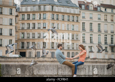 Un couple, homme et femme assis sur le parapet d'un pont sur la Seine. Banque D'Images