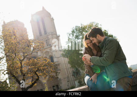 Un couple côte à côte à un écran d'un téléphone intelligent à l'extérieur de la cathédrale Notre Dame de Paris. Banque D'Images