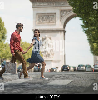 Main dans la main un couple carrying shopping bags et traverser la route Banque D'Images