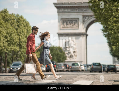 Main dans la main un couple carrying shopping bags et traverser la route par un monument historique Banque D'Images