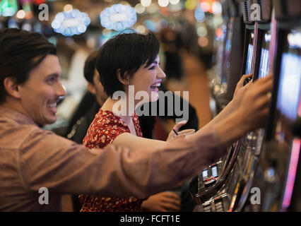 Deux personnes, un jeune homme et femme, en jouant aux machines à sous dans un casino. Banque D'Images