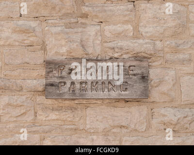 Parking privé signer sculpté en weathered wood sign monté sur mur de briques de ciment gris. Banque D'Images