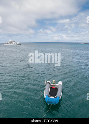 Zodiac intégré sur l'eau vert calme avec un grand yacht dans l'arrière-plan et un ciel nuageux. Banque D'Images